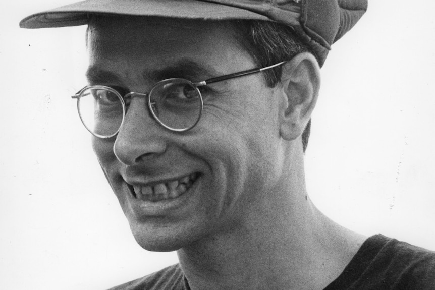 Black and white photo of a man wearing a baseball cap with a Space Shuttle logo on it.