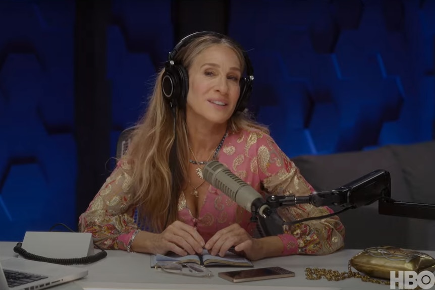 Sarah Jessica Parker sitting in front of a radio microphone with no rings on her fingers. 