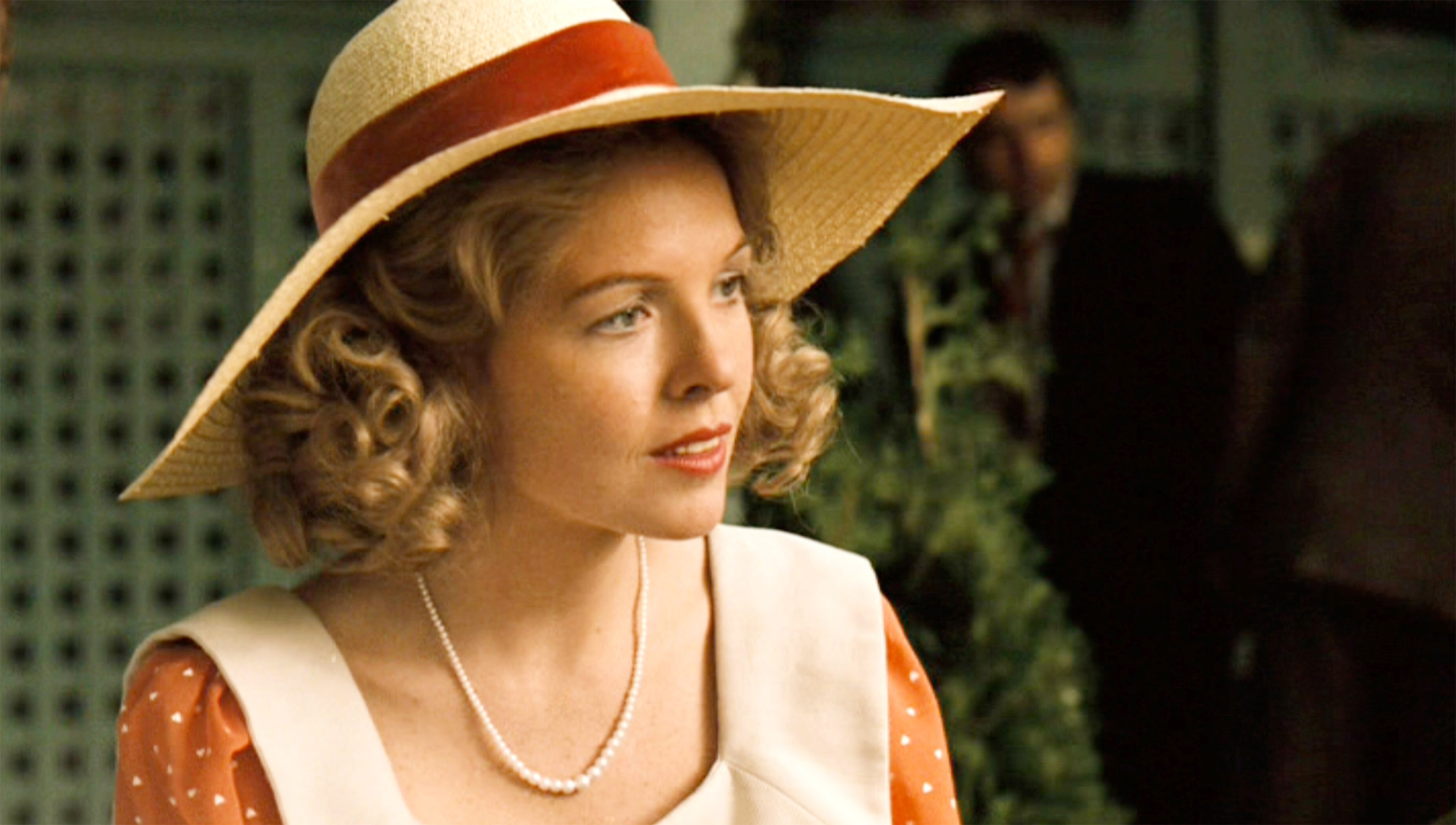 A woman in a sunhat and pearls.