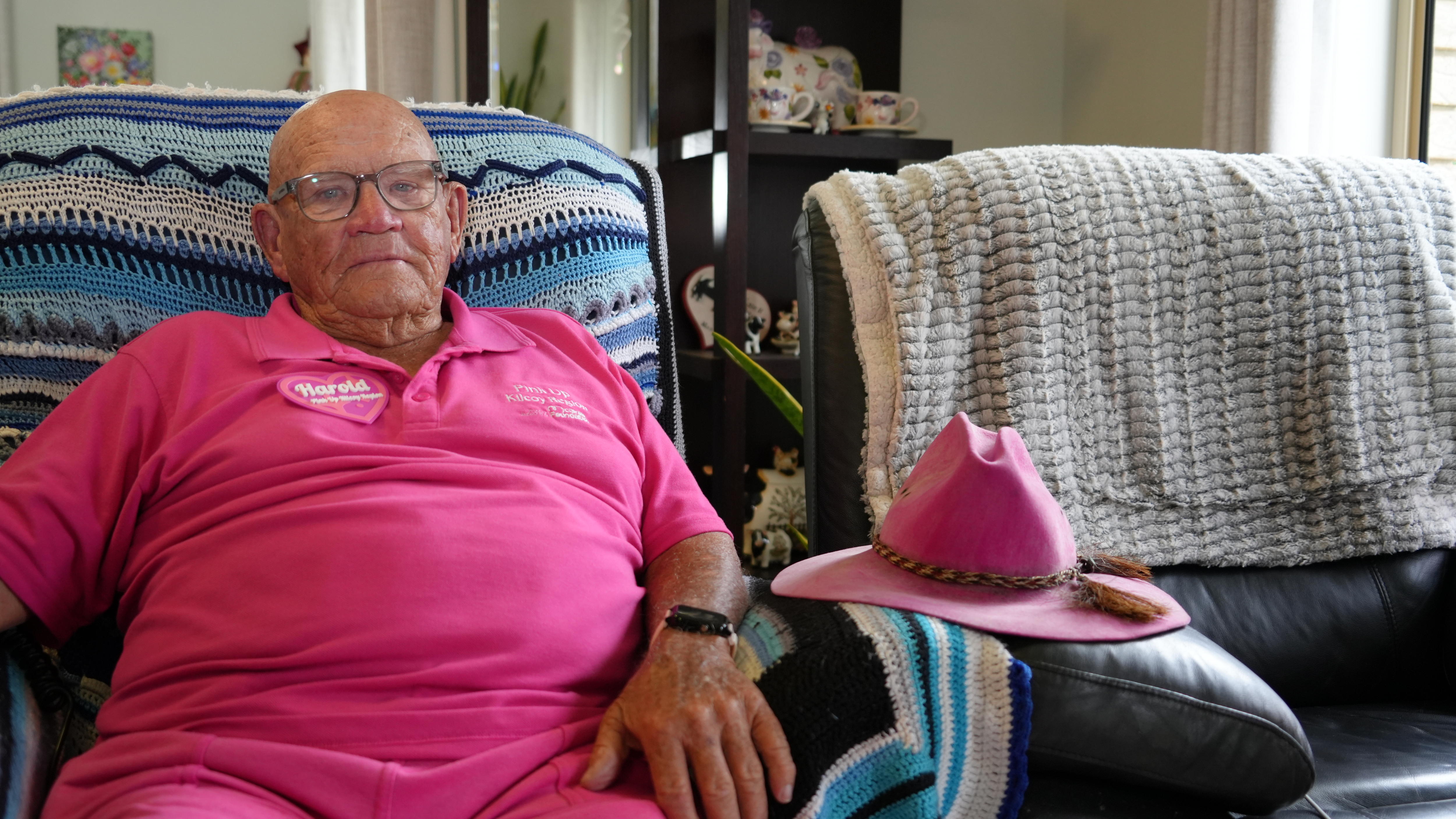 Elderly man in pink sitting on couch