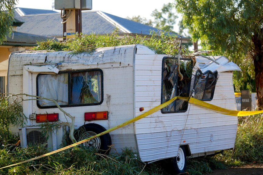 A white caravan crushed by trees after a storm in Broken Hill. 