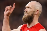 A Melbourne AFL player sticks a finger on his right hand in the air as he celebrates kicking a goal.
