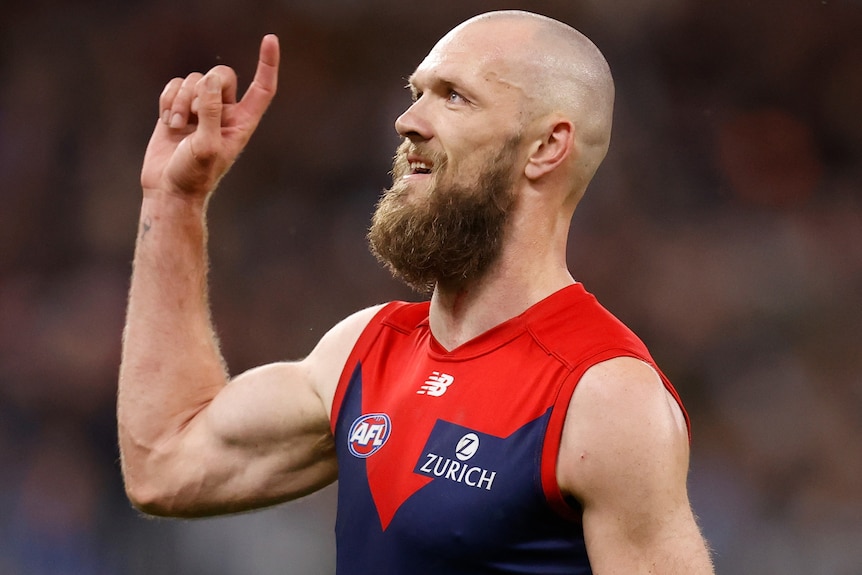 A Melbourne AFL player sticks a finger on his right hand in the air as he celebrates kicking a goal.