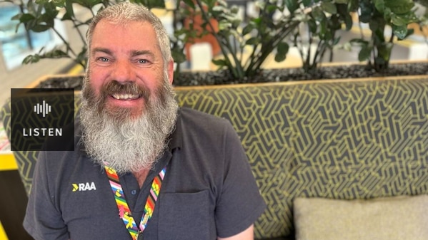 man with short grey hair and long grey beard smiling on a couch in black polo shirt and colourful lanyard. Has Audio.