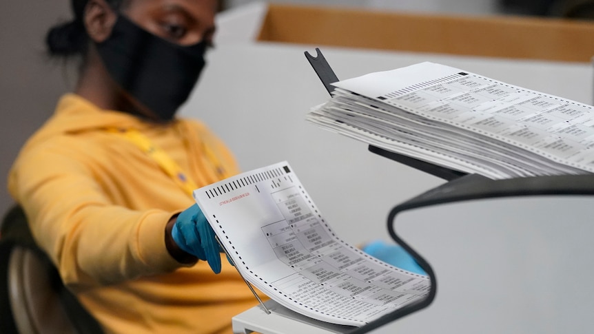 a county election worker scans mail-in ballots at a tabulating area at the Clark County Election Department in Las Vegas