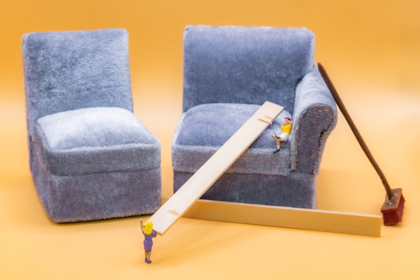A photo of miniature people building a couch.