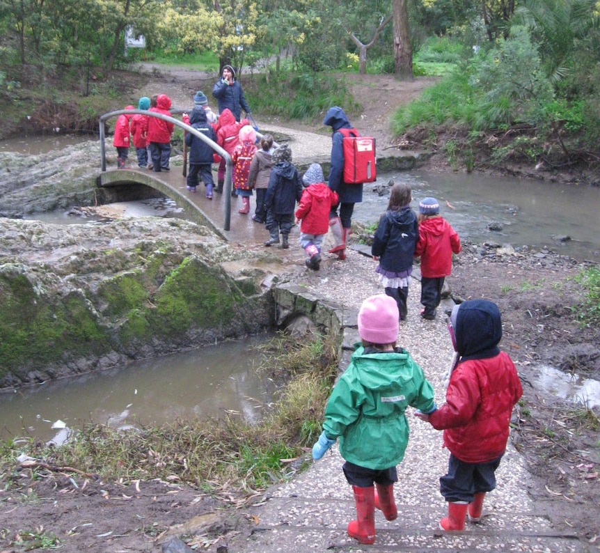 Kids walking in nature, crossing a stream.