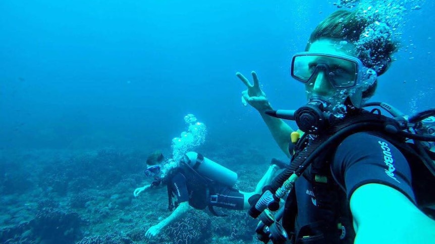 Man taking a photo of himself and another person underwater in diving gear