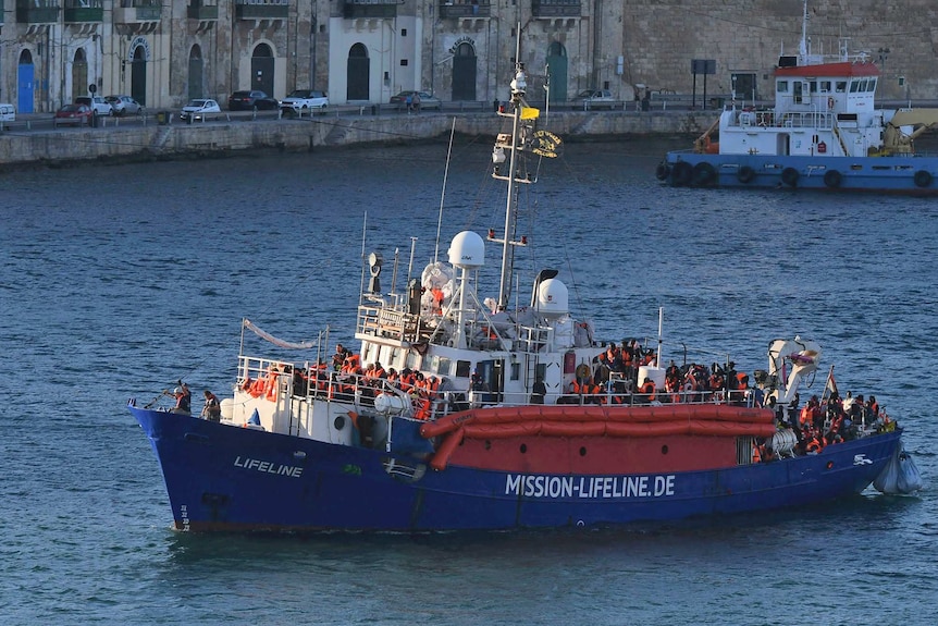 A wide-view photo shows a ship carrying 234 migrants sailing towards a port.