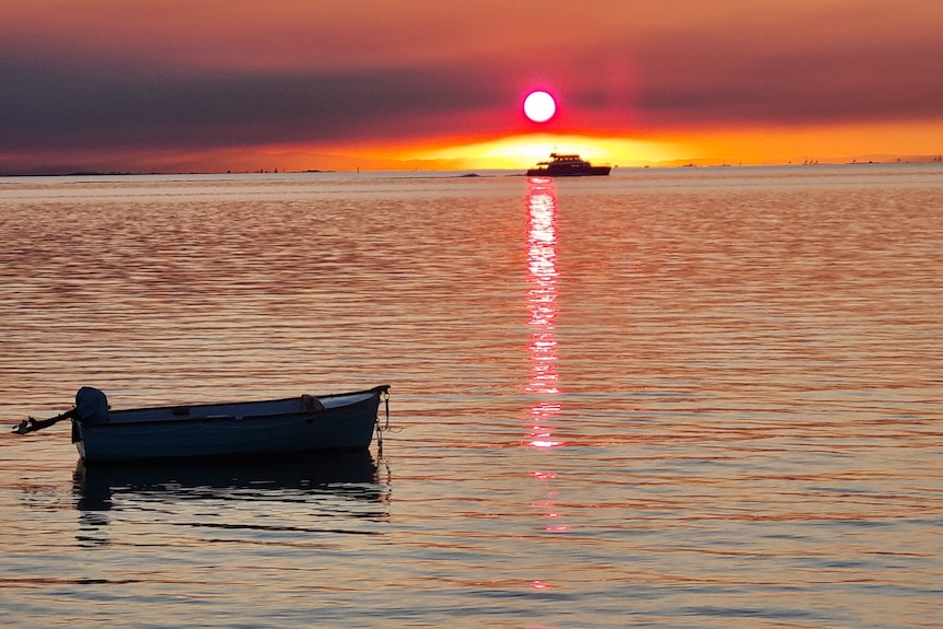 Sunset from Dunwich North Stradbroke Island with orange sky in the distance boat in the foreground