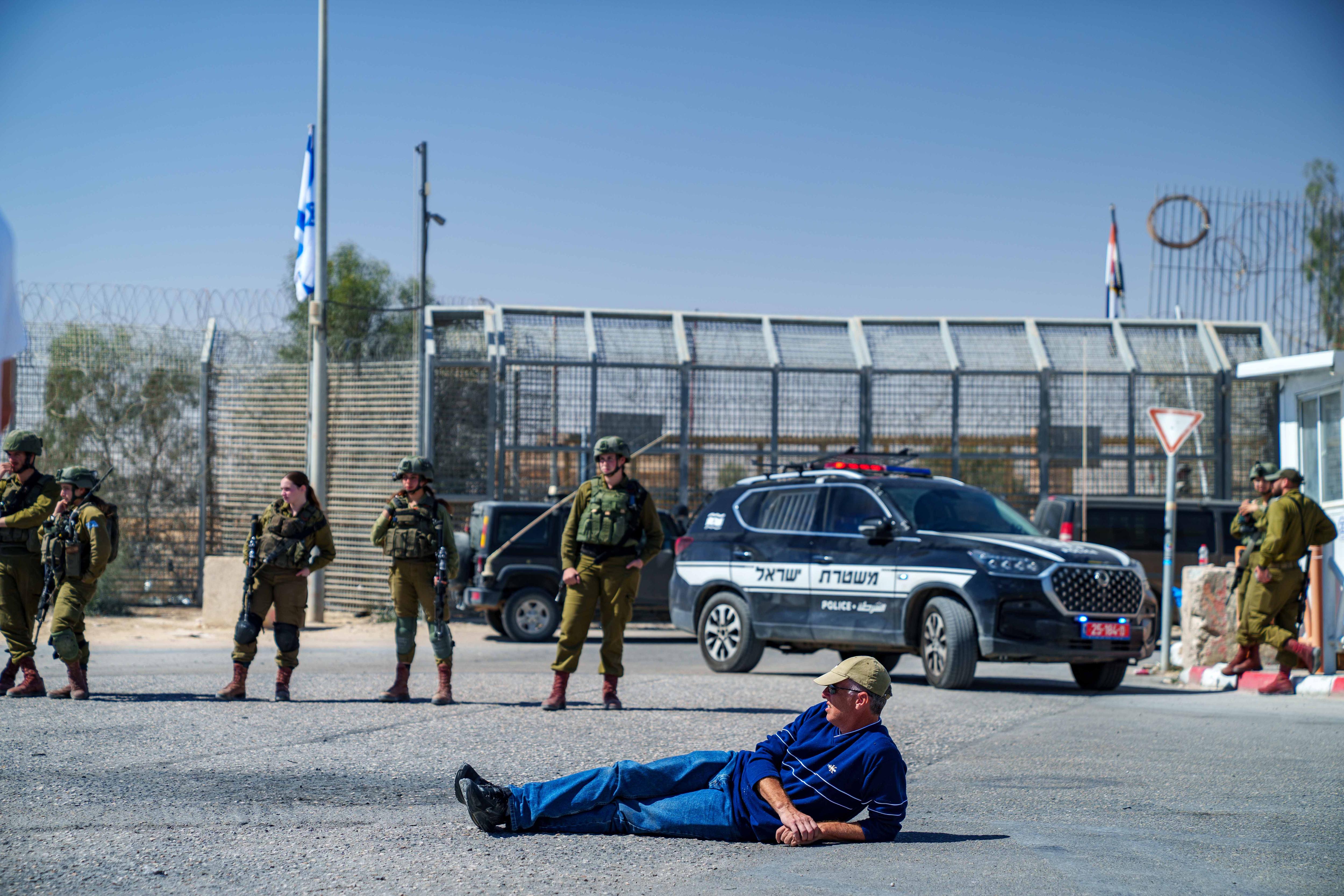 A man lies on the road calmly near a row of police 