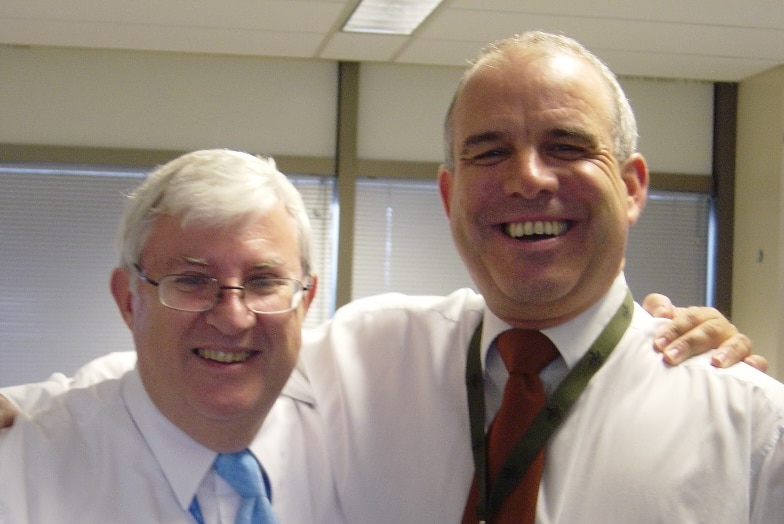 A smiling Graham Blewitt and Bob Reid with arms on each other's shoulders