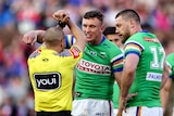 A Canberra NRL player looks at a referee who is holding his hands crossed in an 'X' shape.
