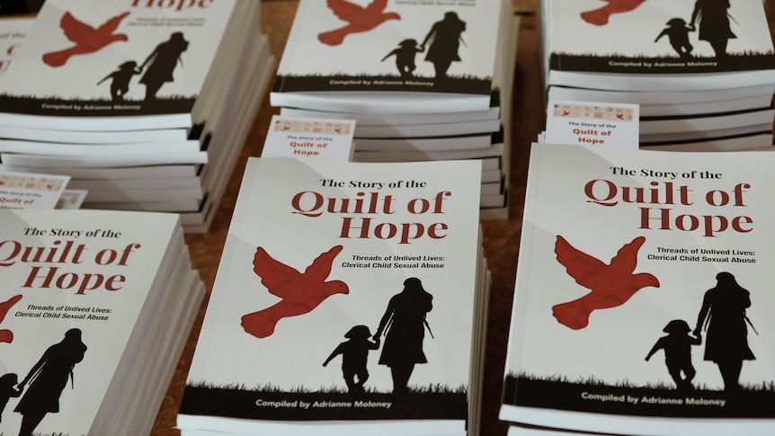 A group of books with the title The Quilt of Hope and a red dove on the cover. 
