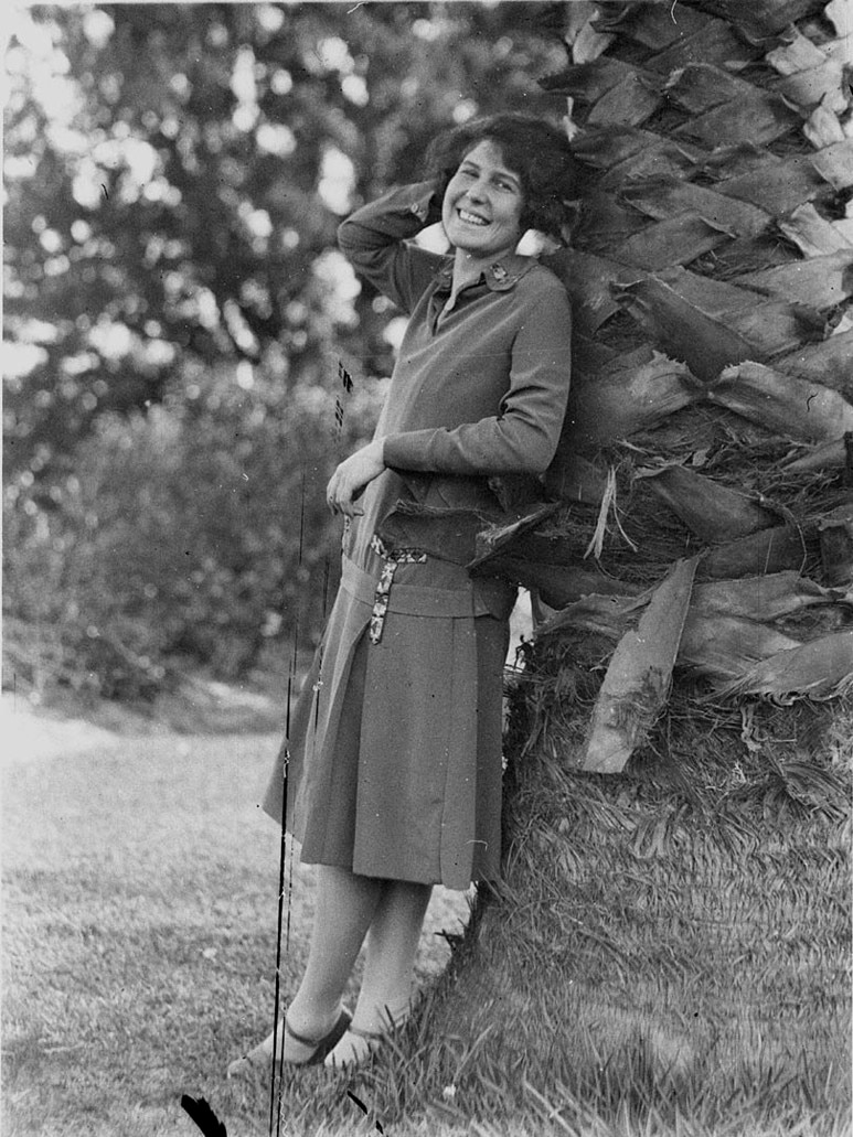 Black and white photo of Beryl Mills leaning against a tree.