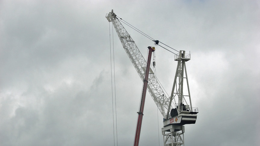 Two cranes work on a city building in Hobart