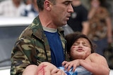 A Russian Interior Ministry officer carries an injured girl after she was released from the school.