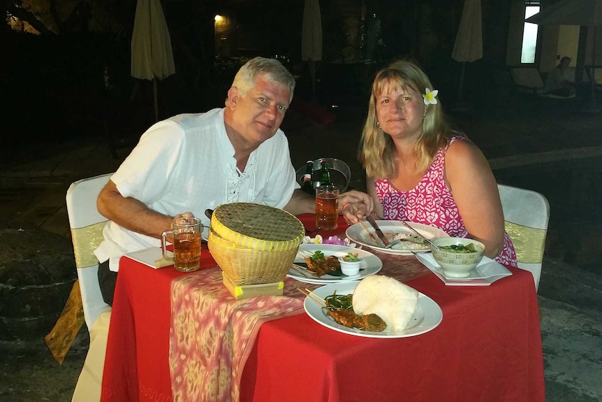 A man and woman eating dinner at a restaurant while on holiday in a tropical Asian location.