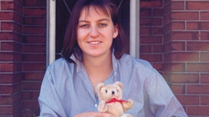 Missing Perth woman Julie Cutler holds a small teddy bear in front of a house.
