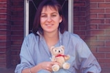 Missing Perth woman Julie Cutler holds a small teddy bear in front of a house.