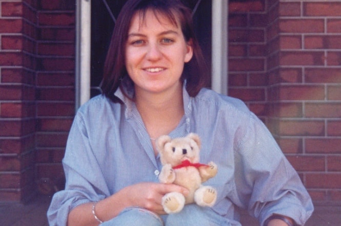 Missing Perth woman Julie Cutler holds a small teddy bear in front of a house.