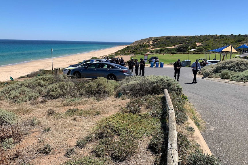 A wide shot of emergency searchers and police standing out the front of Maslin Beach