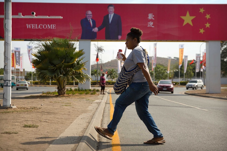 A woman walks past one of many signs dotted around Port Moresby in anticipation of President Xi Jinping's visit to Papua New Guinea