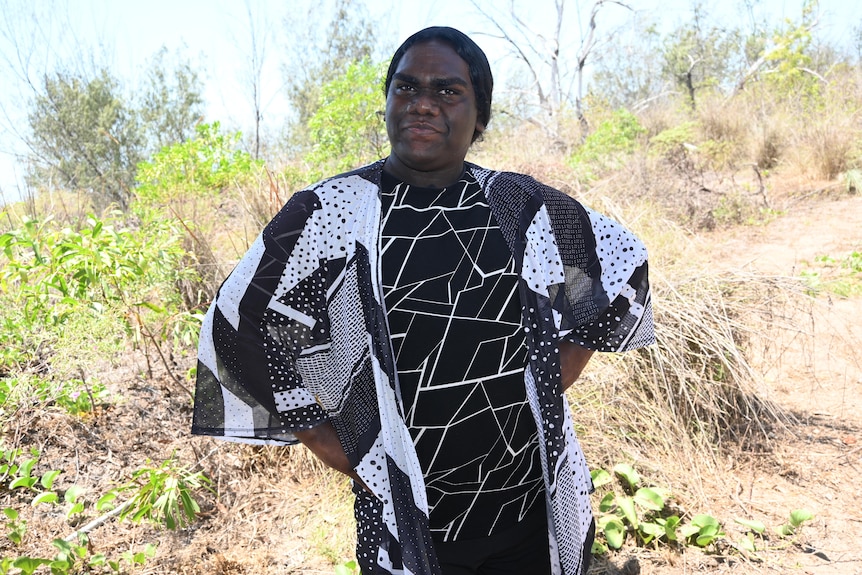 a person wearing a black and white geometric patterned garment in the bush