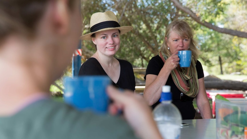 Teacher Anita Harding, flanked by her aide Sharon Pemberton, smiles as she listens to a parent, who is drinking a cup of tea.