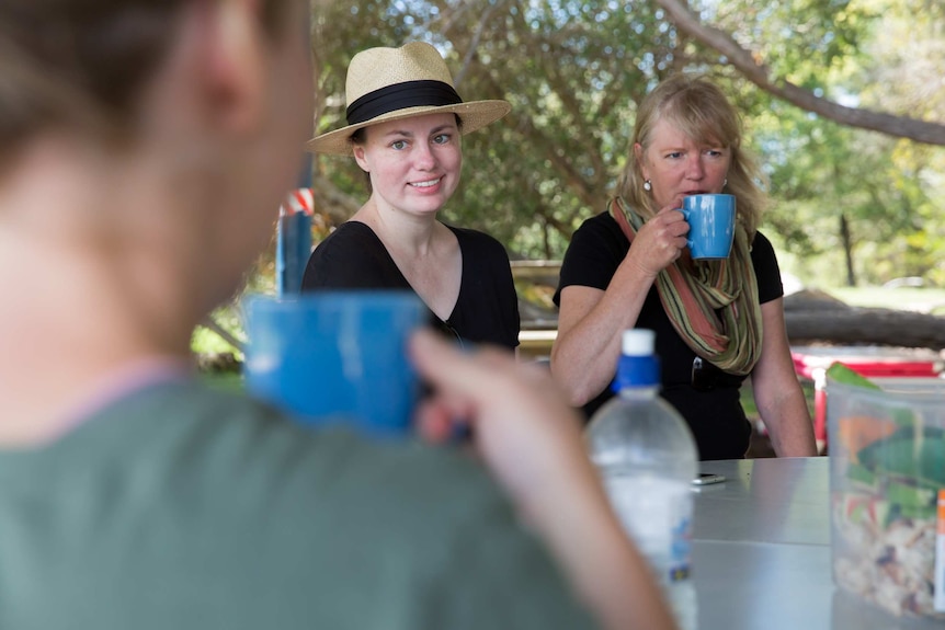 Teacher Anita Harding, flanked by her aide Sharon Pemberton, smiles as she listens to a parent, who is drinking a cup of tea.