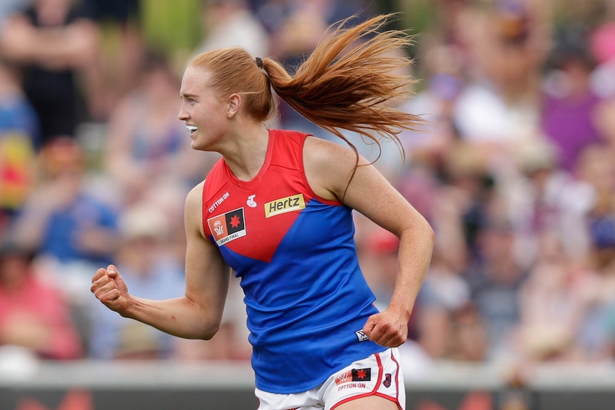A Melbourne AFLW player pumps her right fist as she celebrates a goal in the grand final.
