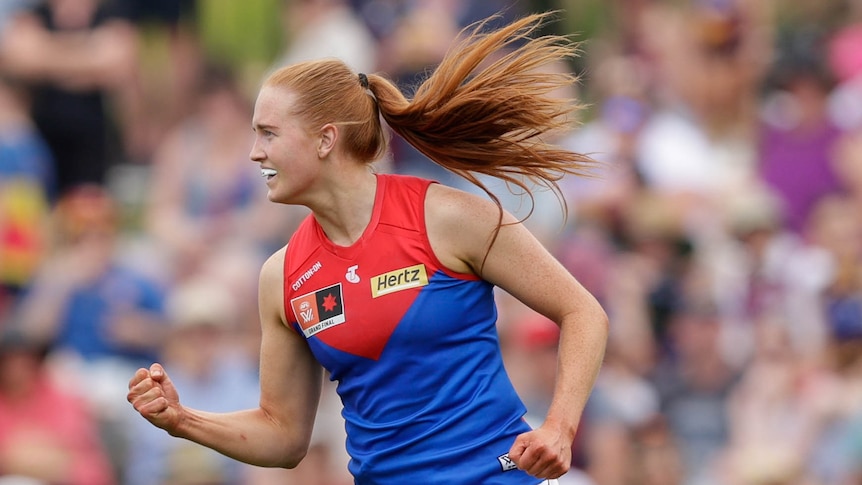 A Melbourne AFLW player pumps her right fist as she celebrates a goal in the grand final.