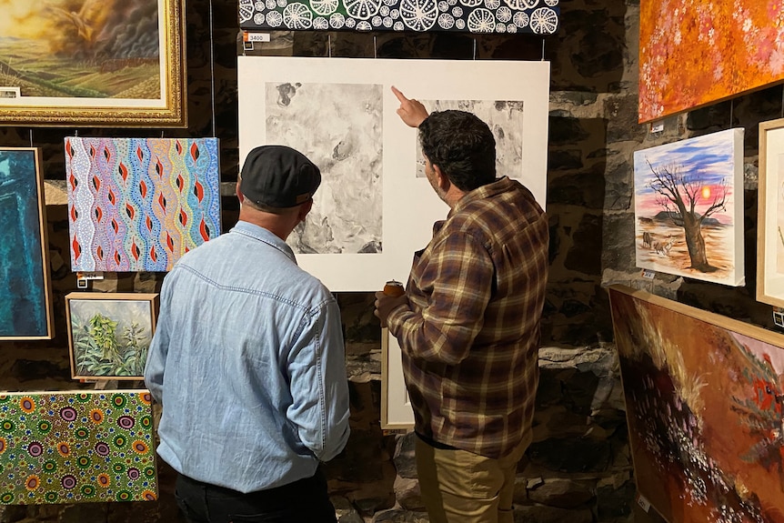 Two men looking at an artwork.