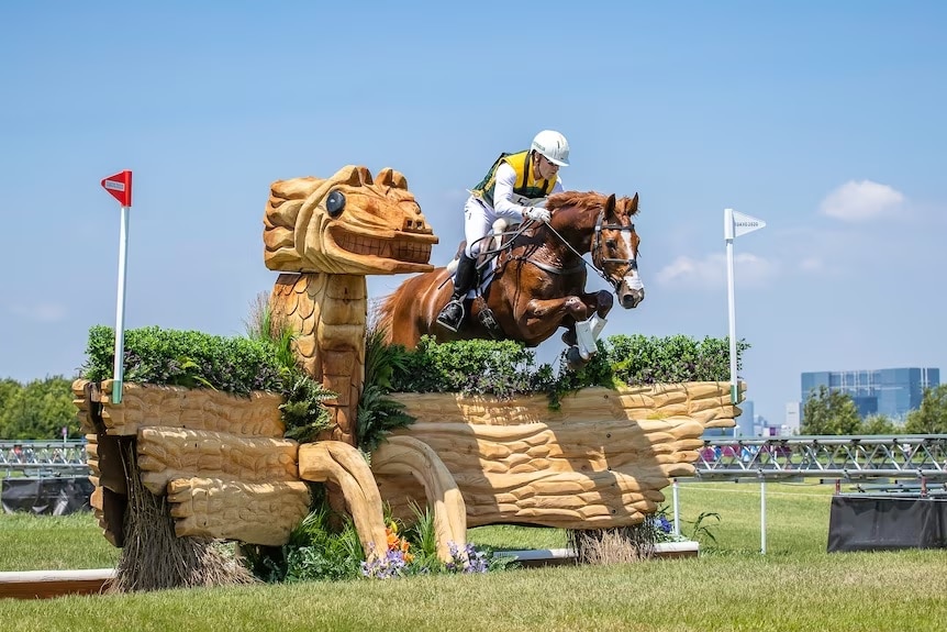 Olympian rider jumps a brown horse over an ornate cross country jump