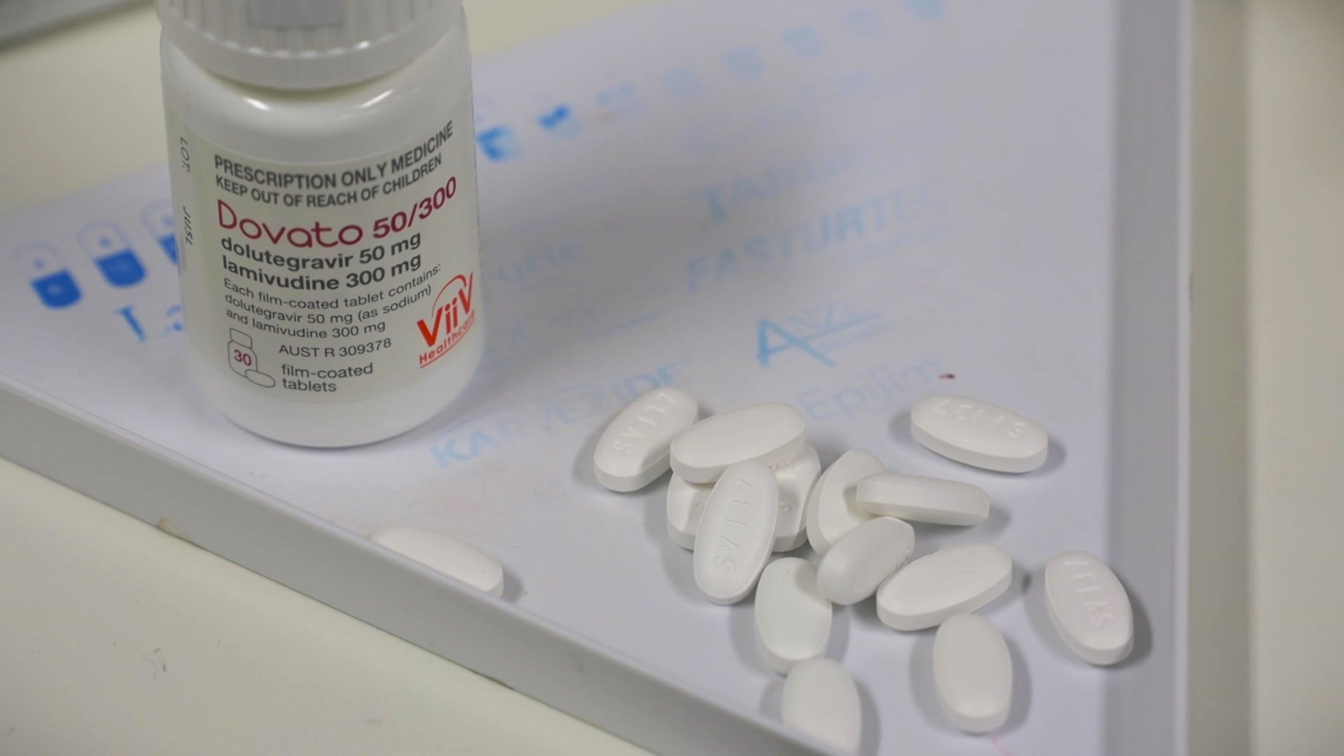 White pills spilling out of a box onto a white tabletop