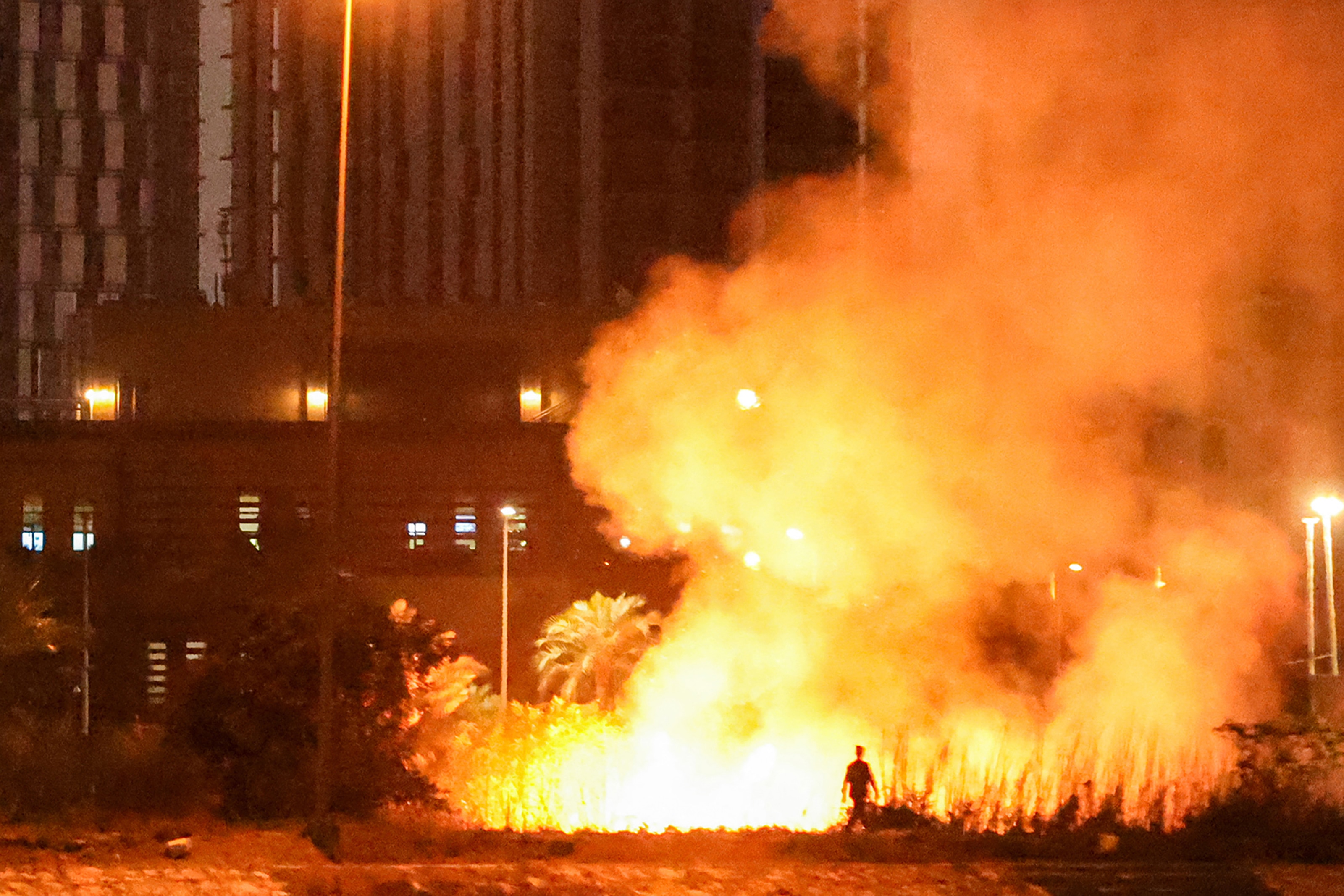 A massive fire blazes outside a building at night