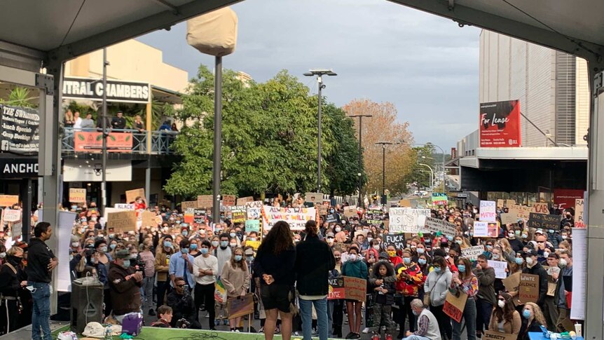 A wide shot of the stage in Wollongong Mall full of people protesting