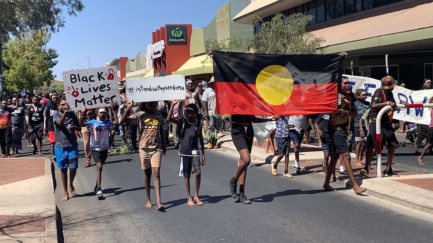 Hundreds of people line the streets of Alice holding flags' and banners.