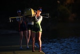 A woman in the Australian Olympic uniform carries out a rowing boat.