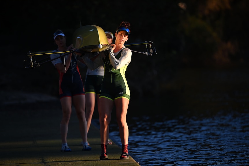 Una donna in uniforme olimpica australiana va su una barca a remi.
