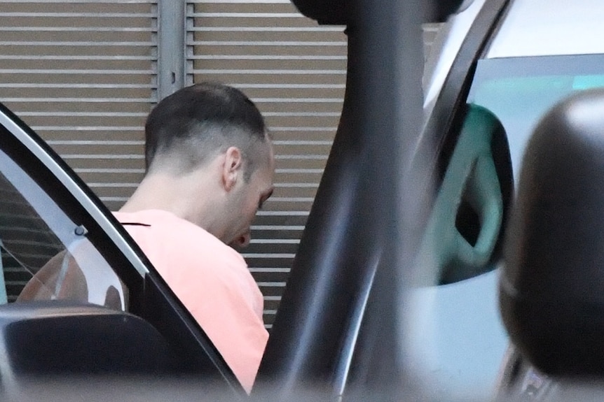 A man wearing an orange jumpsuit gets into a vehicle