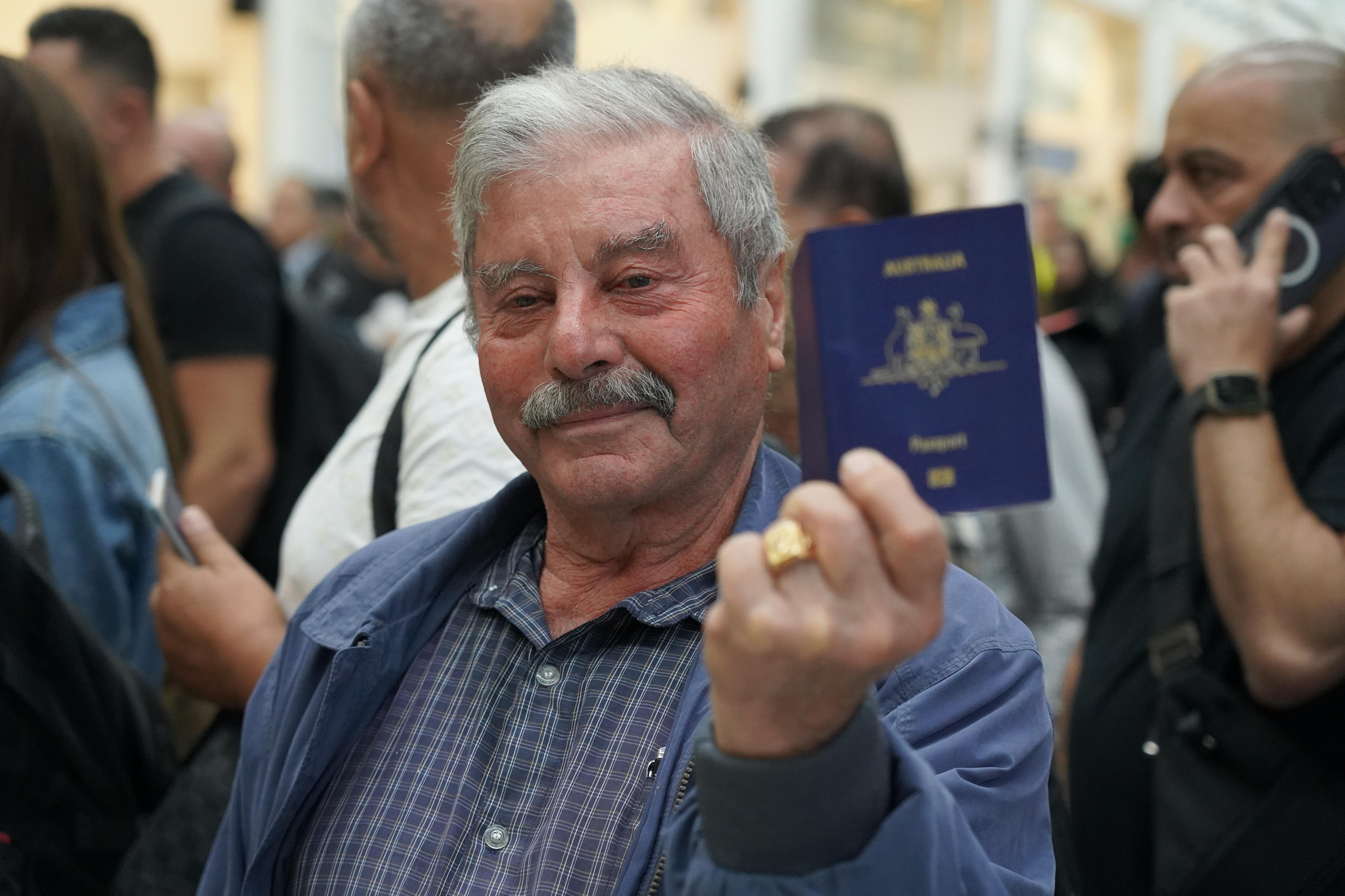An older man holding up an Australian passport. 