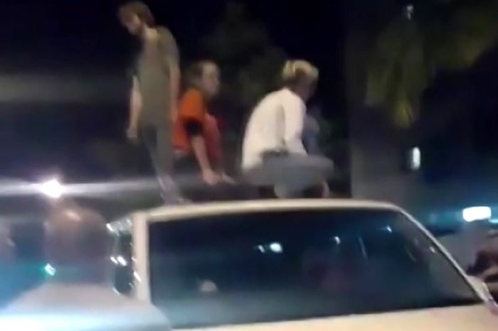 Three people standing on the roof of a white van