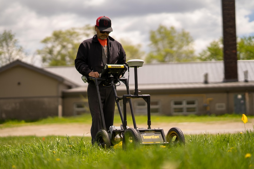 Man walking a sonar machine across a lawn.