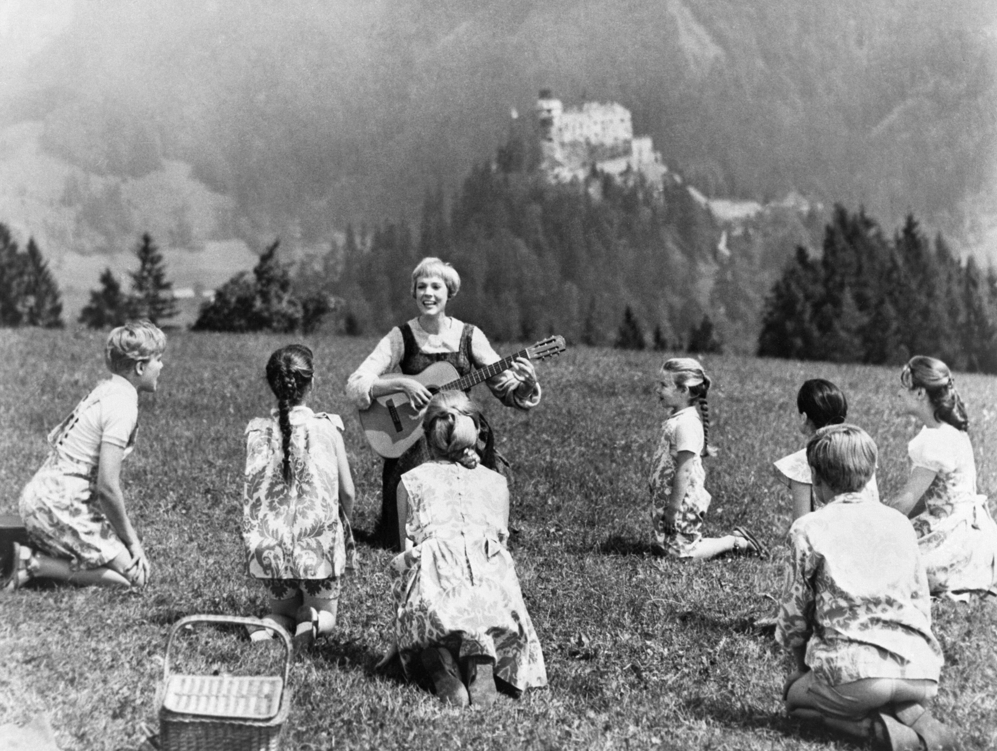 Acting as the governess, Julie Andrews as Maria sings to her charges while sitting in a pasture on The Sound of Music