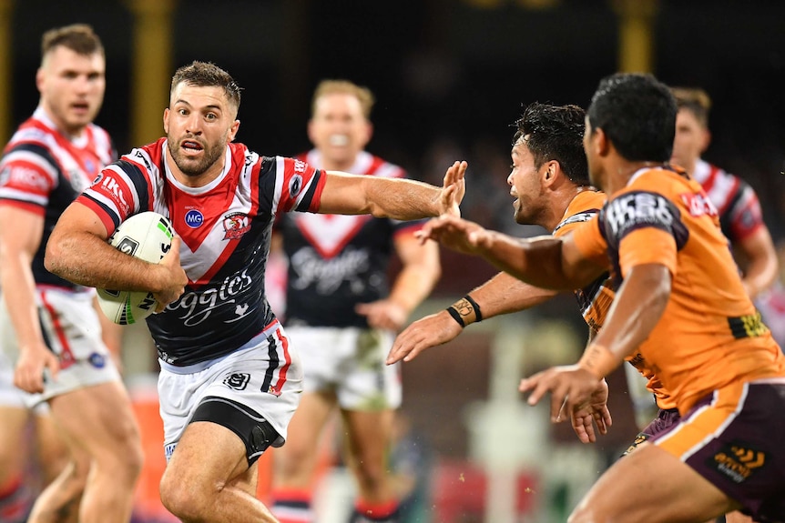 James Tedesco uses his left hand to fend off the attempted tackles of Alex Glenn and Anthony Milford.