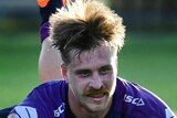 A Melbourne Storm NRL player slides on the ground with the ball under his left arm to score a try against North Queensland.