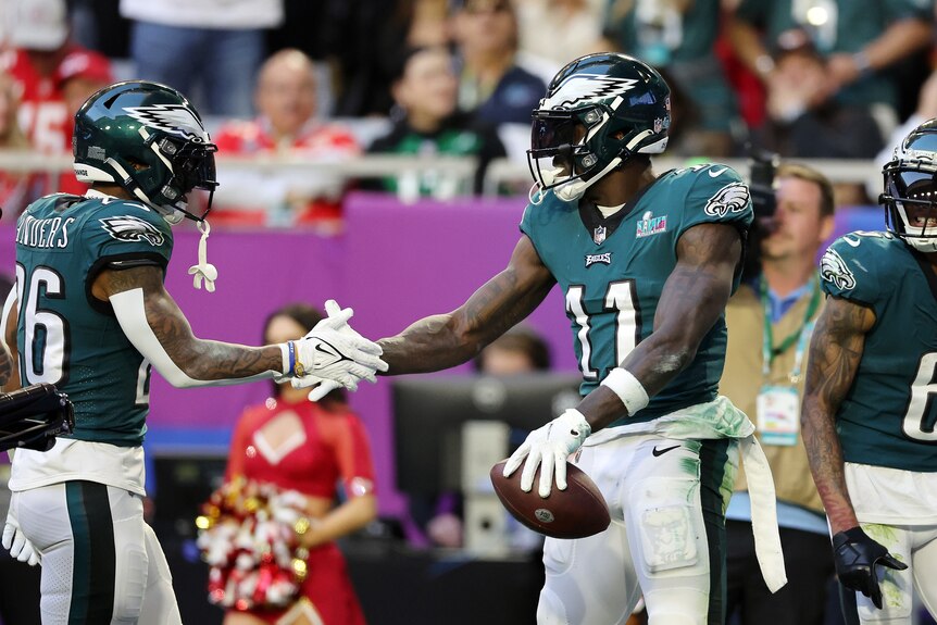 Two Philadelphia Eagles players stand in the end zone and shake hands in celebration of a Super Bowl touchdown.
