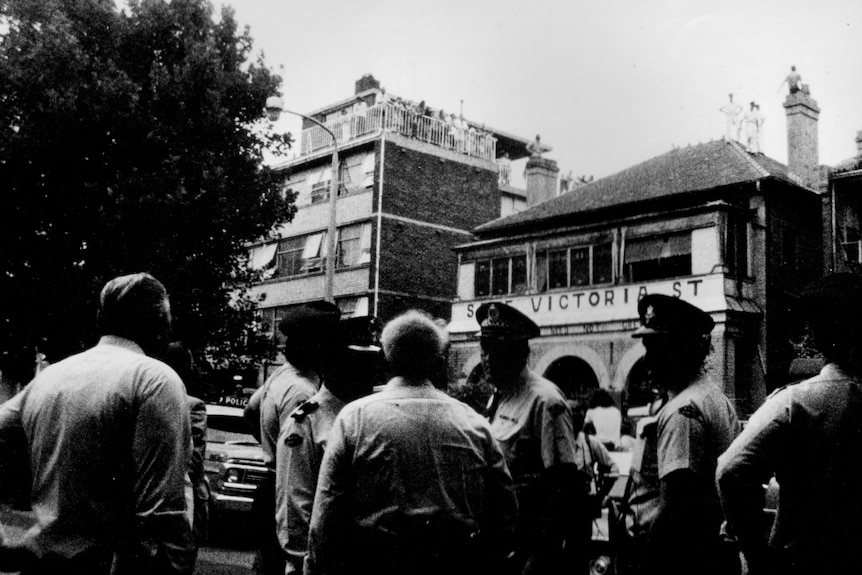 A group of police officers outside a building that is painted with the words 'Save Victoria Street'.