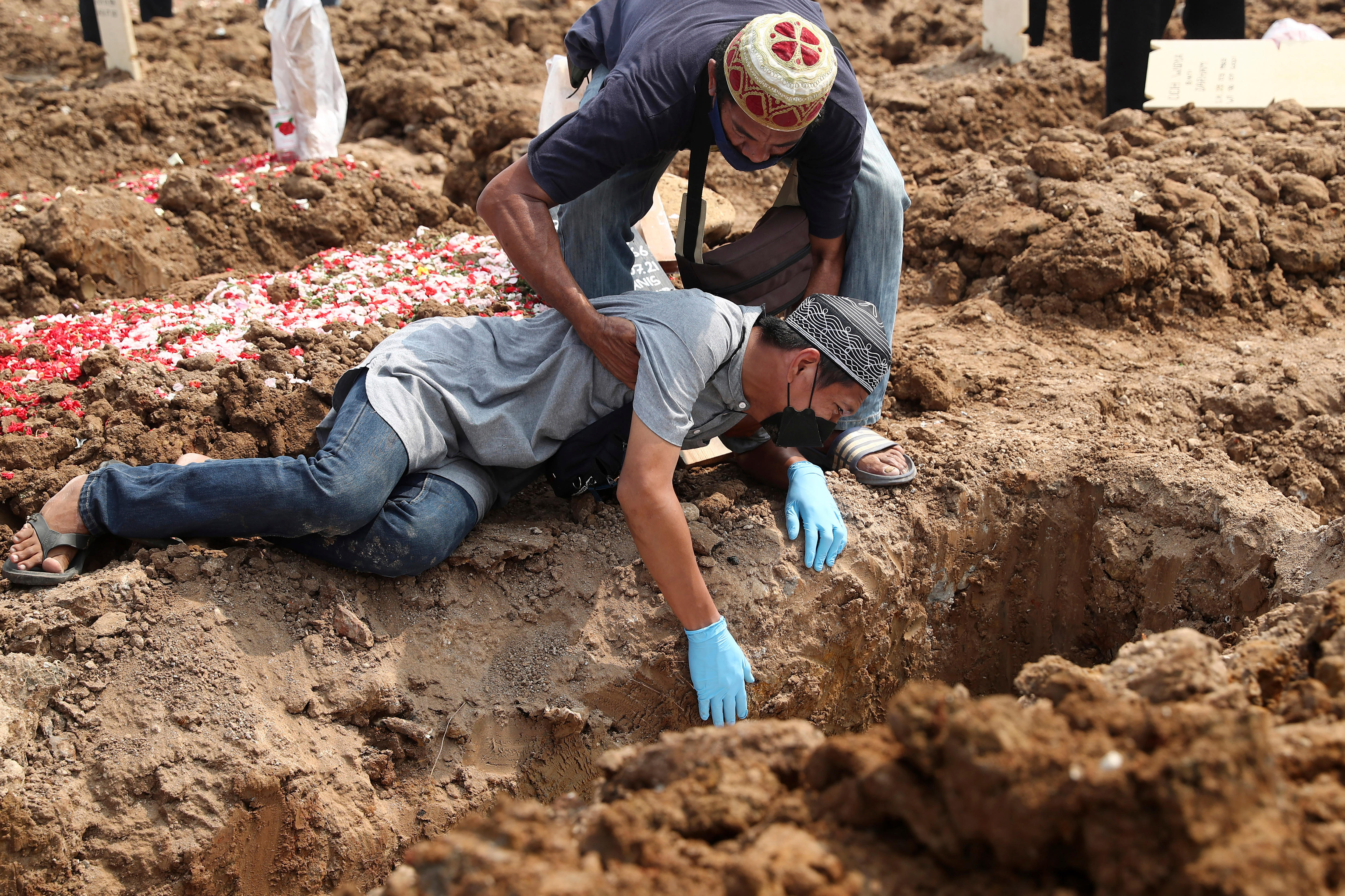 Seorang pria jatuh ke tanah saat dia menangis selama pemakaman kerabatnya